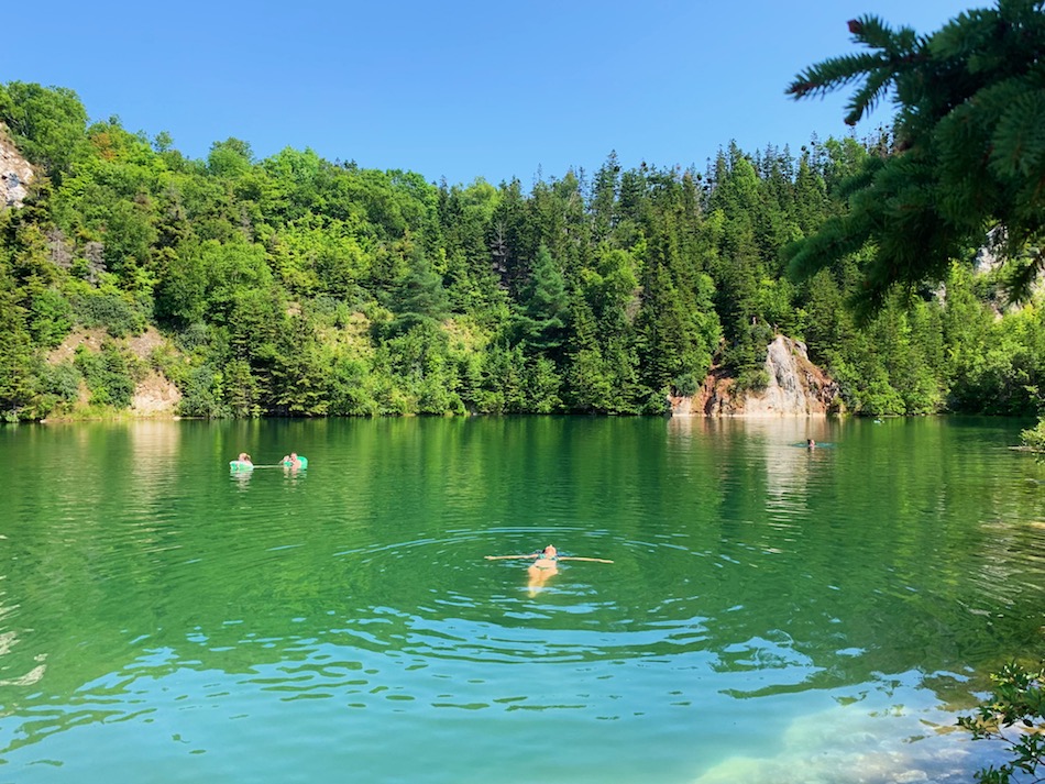 Julia floating the Gypsum Mine swimming hole that is surrounded by forest. 