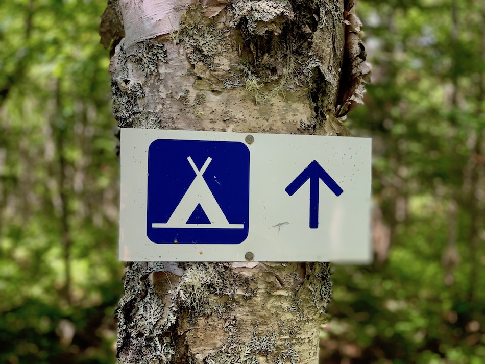 A sign indicating a camping site a head. 