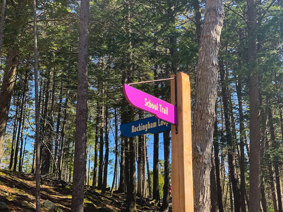 Trail signs indicating which direction to go for either the School Trail or the Rockingham Loop in Hemlock Ravine Park.