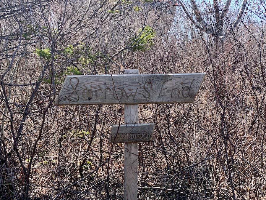Wooden sign that says Sorrow's End and an arrow pointing to the trail. 
