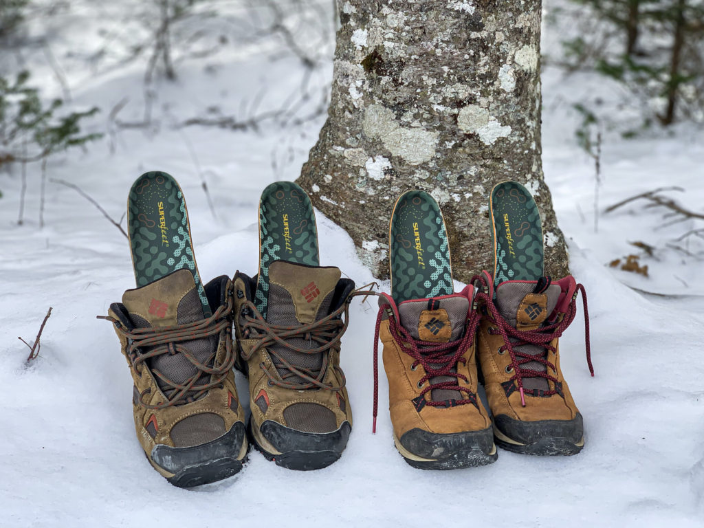 Mens and womens hiking boots in the snow with Superfeet Adapt Hike Max Insole sticking out of them. 