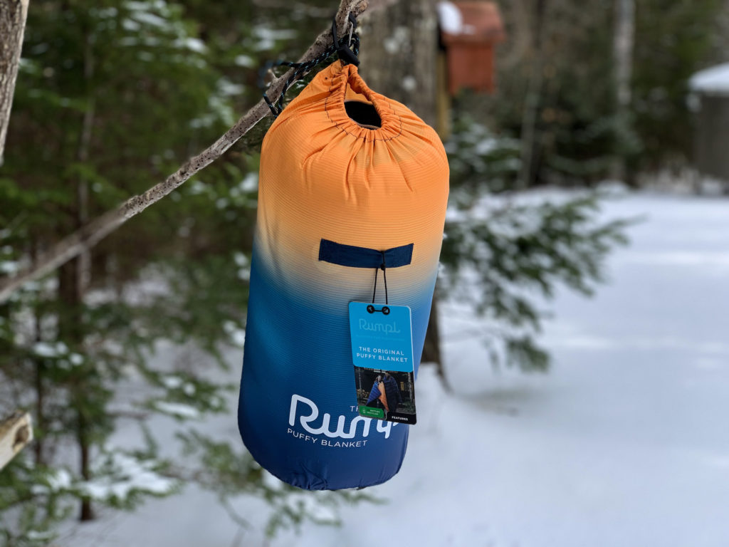 The Rumpl Original Puffy Blanket hanging in its bag on a tree branch.
