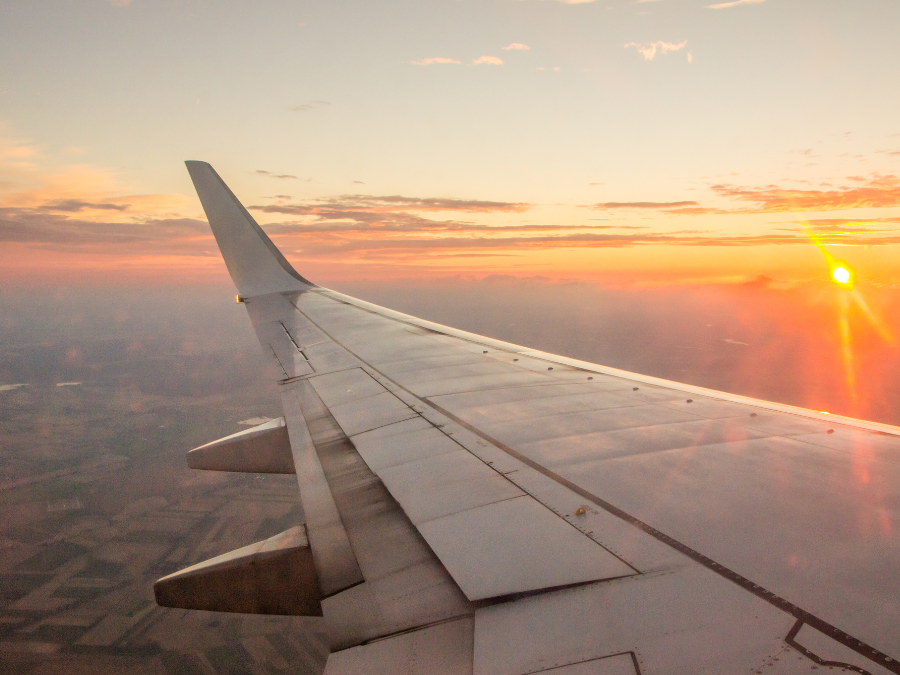 Travel on a budget: A plane wing with a sunset in the background.