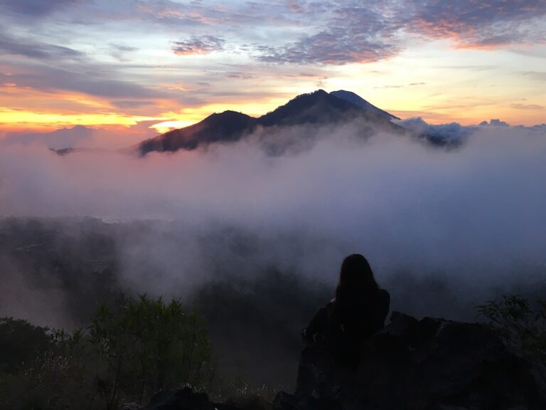 Julia sitting in front of a sunrise at the top of Mount Batur